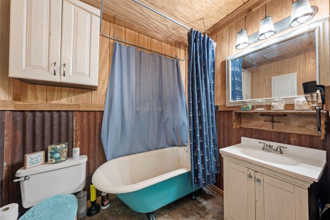 Full bath with toilet, vanity, wood walls, and shower / tub combo with curtain | Image 11