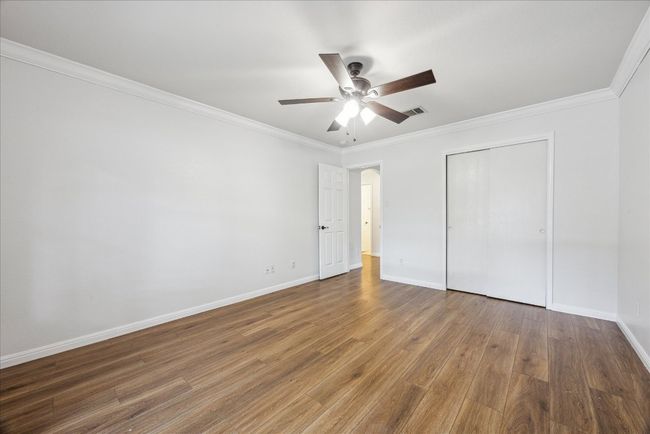 Oversized secondary bedroom with crown molding, ceiling fan, and closet with sliding doors | Image 26