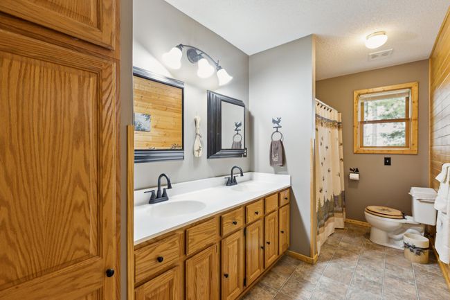 Newly remodeled upper level bath features double sinks with modern faucets, gorgeous oak cabinets and framed mirrors | Image 21