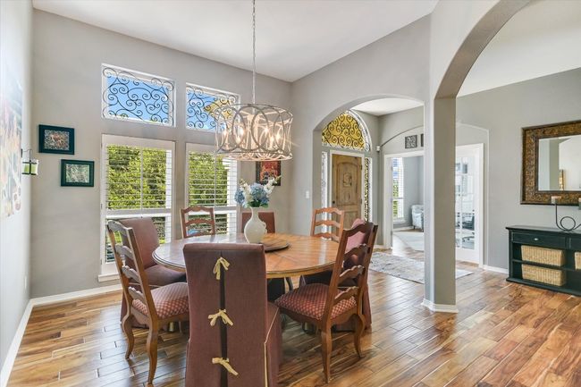 Dining room with arched walkways, a chandelier, plenty of natural light, and wood finished floors | Image 9