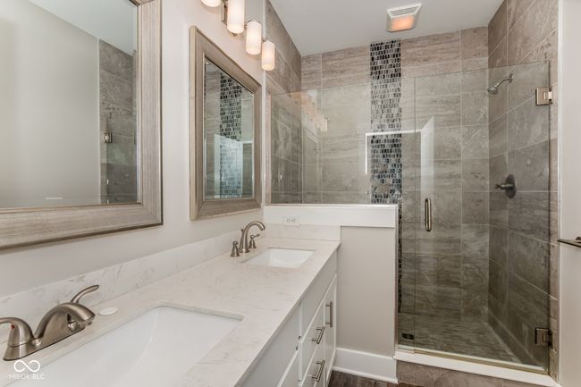 bathroom featuring a sink, double vanity, and a stall shower | Image 7