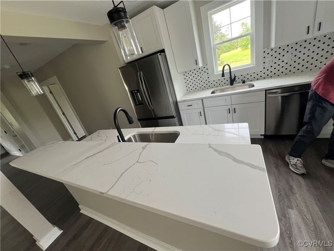 Kitchen featuring stainless steel appliances, white cabinets, a sink, and dark wood-type flooring | Image 5