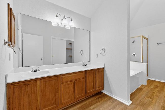 Bathroom with a shower stall, wood finished floors, double vanity, a garden tub, and vaulted ceiling | Image 18