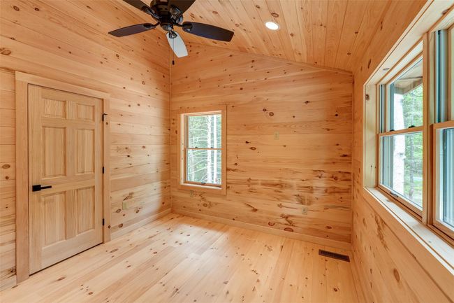 Spare room with wooden walls, a relaxing sauna, vaulted ceiling, wooden ceiling, and light wood-style floors | Image 32