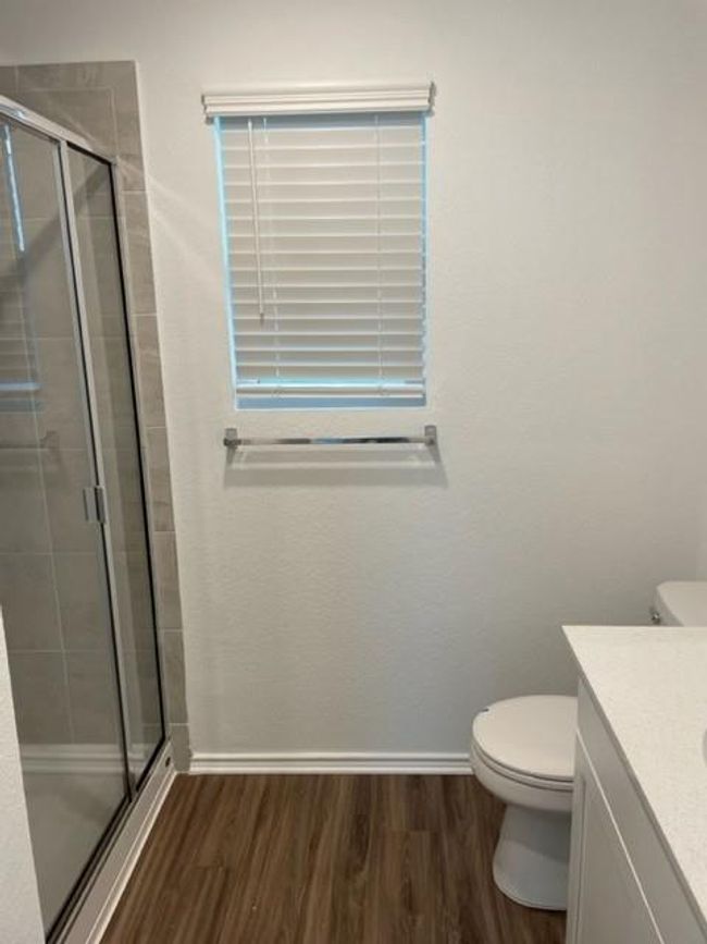 Full bath featuring wood finished floors, a shower stall, toilet, and vanity | Image 11