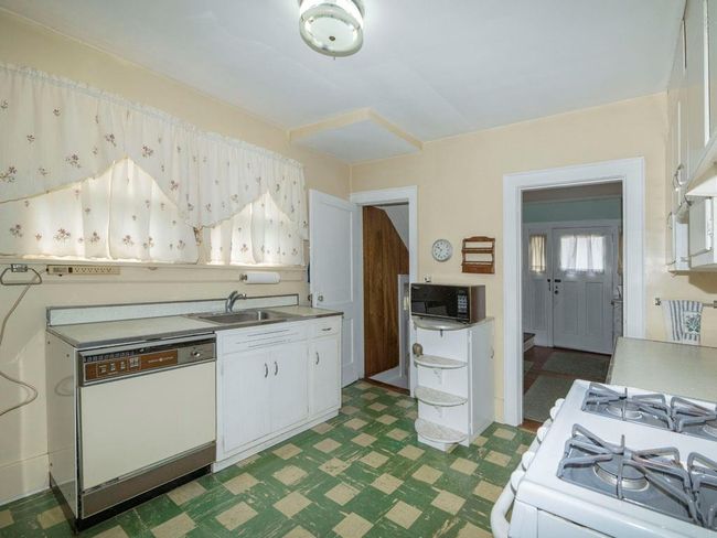 Kitchen featuring white appliances, dark floors, white cabinetry, and light countertops | Image 15