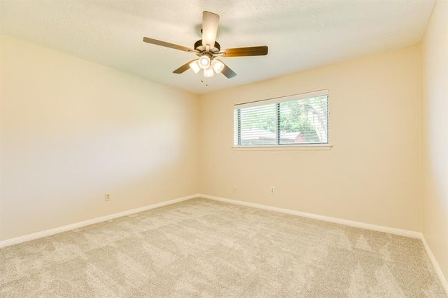 Bedroom 3 at the back of the home with a ceiling fan and new carpet. | Image 24