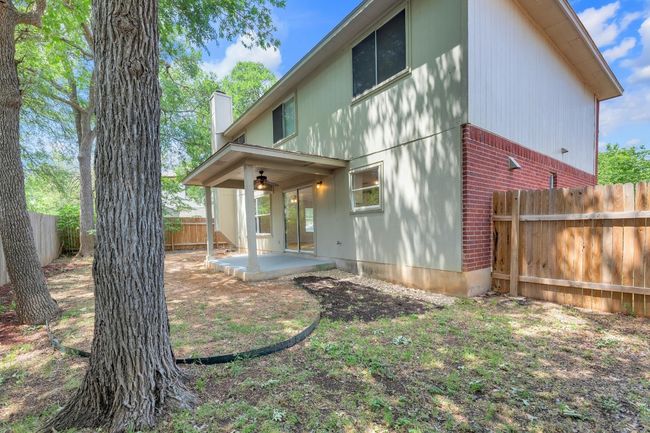 Back of property featuring a fenced backyard, a chimney, brick siding, ceiling fan, and a patio | Image 35