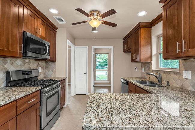 Kitchen with appliances with stainless steel finishes, light stone counters, a ceiling fan, light tile patterned floors, and recessed lighting | Image 11