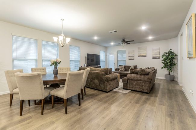 Dining space featuring light wood finished floors, a chandelier, baseboards, plenty of natural light, and recessed lighting | Image 8
