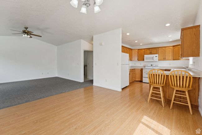 Kitchen with white appliances, ceiling fan, a peninsula, open floor plan, and recessed lighting | Image 10