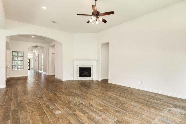The family room, featuring corner gas log fireplace, with a view into the entrance hall with tile flooring. | Image 27