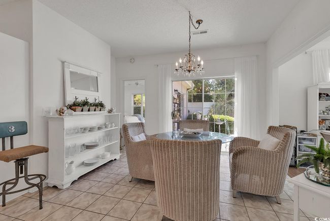 Dining area with a chandelier, light tile patterned floors, and a textured ceiling | Image 16