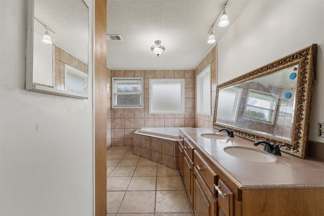 Full bathroom with a bath, double vanity, tile patterned floors, and a textured ceiling | Image 19