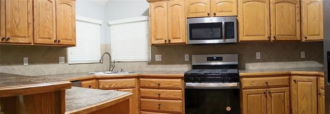 Kitchen with stainless steel appliances, decorative backsplash, and light countertops | Image 8
