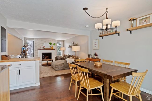 Dining space featuring dark wood-type flooring, a brick fireplace, a chandelier, and baseboards | Image 9