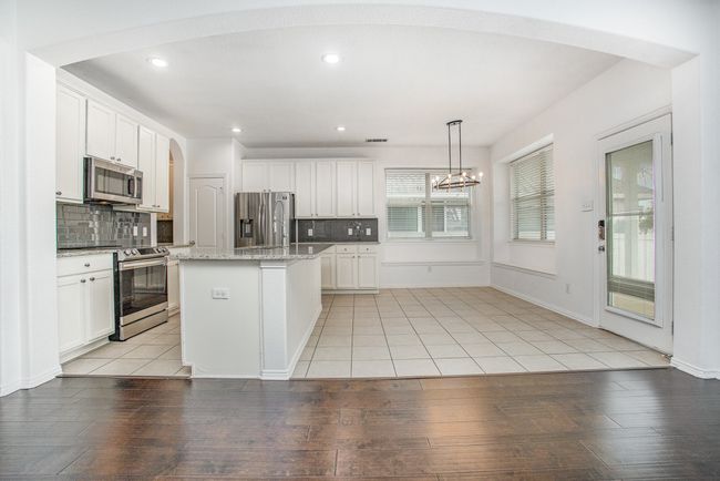 Kitchen with white cabinetry, backsplash, light granite countertops, and stainless steel appliances | Image 9