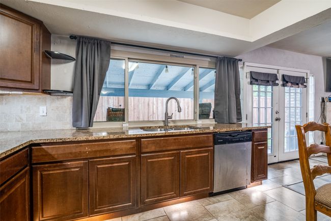 Kitchen with dishwasher, light stone counters, decorative backsplash, and light tile patterned floors | Image 10