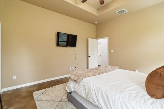 Bedroom with baseboards, a ceiling fan, a raised ceiling, and concrete flooring | Image 22