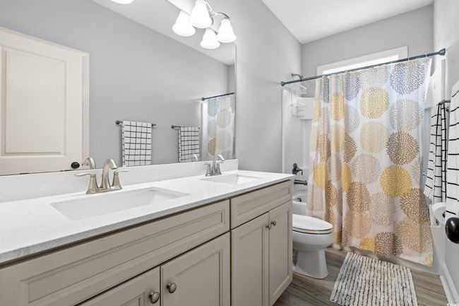 Full bathroom with shower / bathtub combination with curtain, double vanity, and wood finished floors | Image 17
