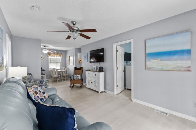 Living room with light wood-style floors, ceiling fan, a textured ceiling, and baseboards | Image 7