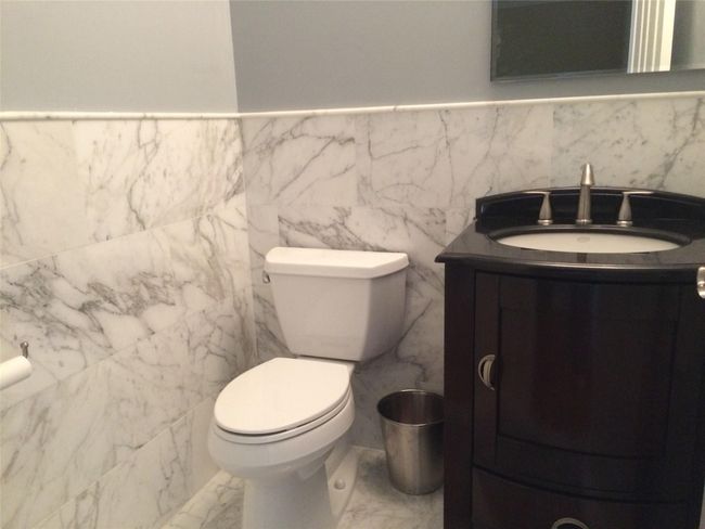 Half bath with vanity, marble finish floors, toilet, and tile walls | Image 8