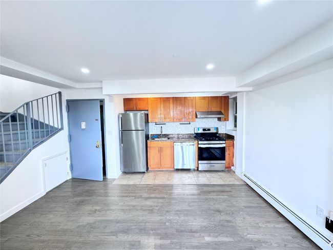 Kitchen with stainless steel appliances, baseboard heating, under cabinet range hood, light wood-type flooring, and recessed lighting | Image 14