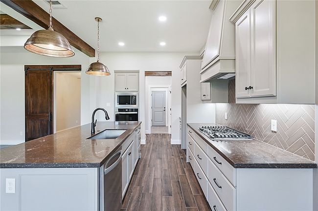 Kitchen featuring a sink, appliances with stainless steel finishes, dark wood-style floors, backsplash, and custom exhaust hood | Image 11