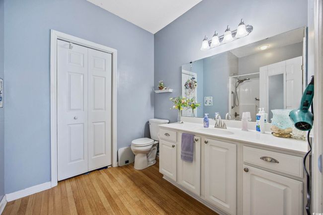 Full bath featuring vanity, toilet, a shower with curtain, wood finished floors, and a closet | Image 20