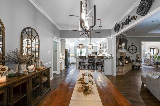 Dining space featuring an inviting chandelier, a fireplace, ornamental molding, baseboards, and dark wood-style floors | Image 15