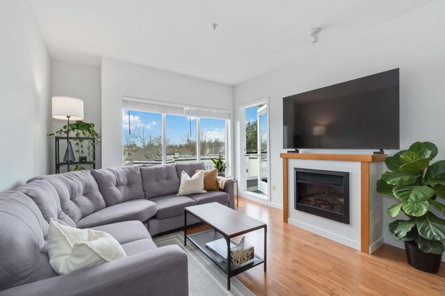 Living area with baseboards, a glass covered fireplace, and light wood-style floors | Image 5