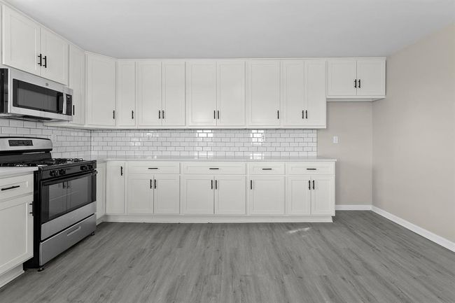 Kitchen with stainless steel appliances, baseboards, light countertops, and light wood-type flooring | Image 6