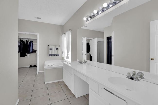 Bathroom with visible vents, tile patterned floors, a sink, a spacious closet, and a bath | Image 18