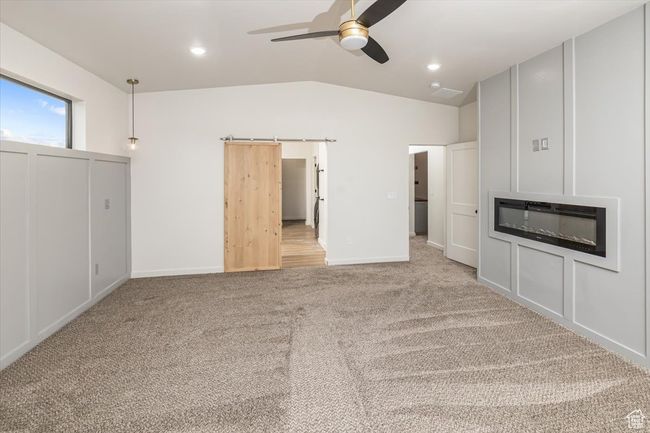 Unfurnished living room featuring a barn door, ceiling fan, light colored carpet, and lofted ceiling | Image 18