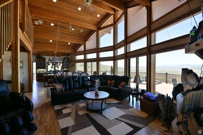 Living area with recessed lighting, wood finished floors, a water view, and high vaulted ceiling | Image 70