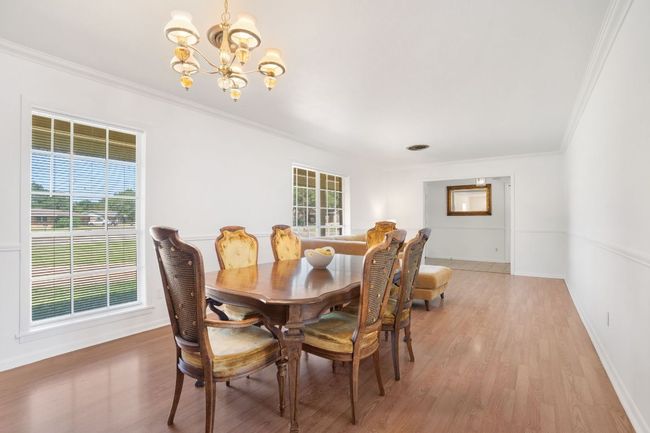 Dining area with a chandelier, ornamental molding, and laminate flooring attached to a sitting room. Imagine hosting your holiday events with an even bigger table! | Image 4