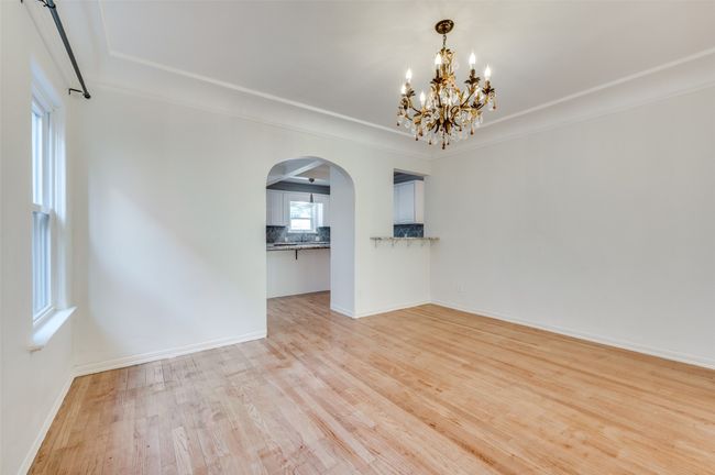 Empty room with arched walkways, a chandelier, light wood-type flooring, and baseboards | Image 11