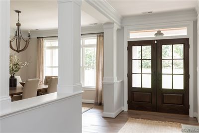 Entryway with light hardwood / wood-style flooring, ornamental molding, an inviting chandelier, french doors, and decorative columns | Image 2