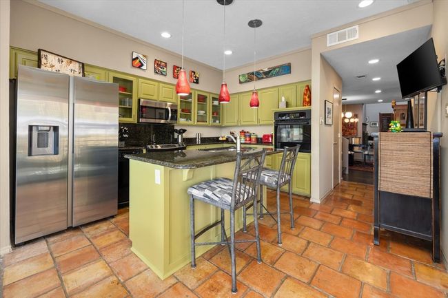 Kitchen with recessed lighting, green cabinetry, stainless steel appliances, instant hot water at sink. Saltillo tile flooring. | Image 19