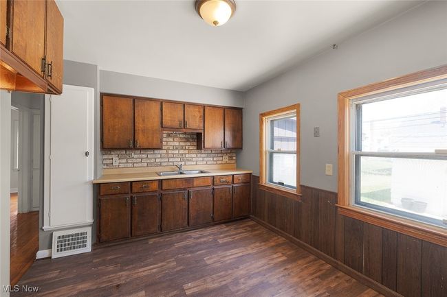 Kitchen with a sink, dark wood-type flooring, visible vents, light countertops, and wainscoting | Image 5