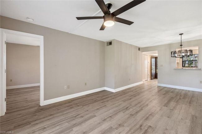 Empty room with ceiling fan with notable chandelier and light wood-type flooring | Image 13