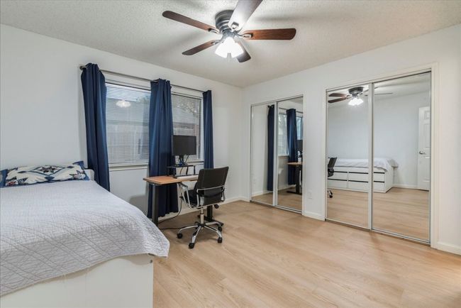 Bedroom featuring two closets, baseboards, a textured ceiling, light wood finished floors, and ceiling fan | Image 11