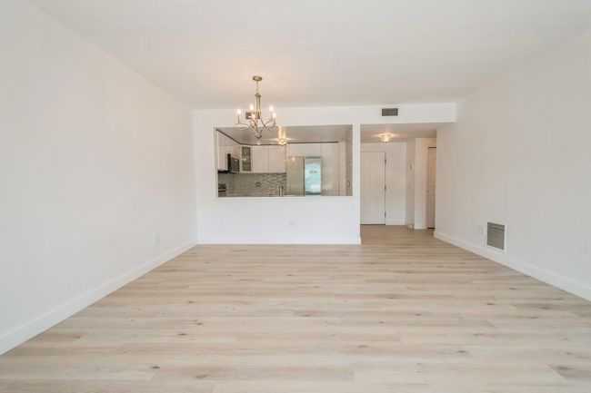 Unfurnished living room with a chandelier and light wood-style floors | Image 8
