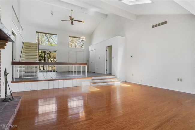 Unfurnished living room featuring beamed ceiling, wood finished floors, visible vents, and high vaulted ceiling | Image 9