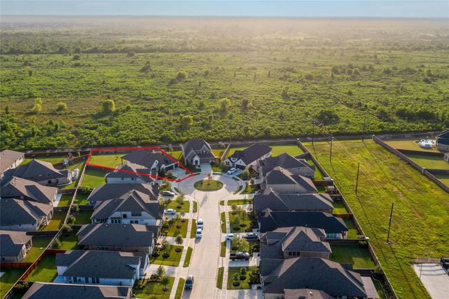 This photo shows a suburban neighborhood with a row of modern houses surrounding a cul-de-sac. The highlighted property is spacious, with a large backyard, and backs onto a vast green space, providing privacy and scenic views. Ideal for those seeking a quiet, family-friendly environment. | Image 46