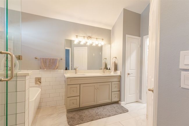 Full bathroom featuring double vanity, a bathtub, and an enclosed shower | Image 18