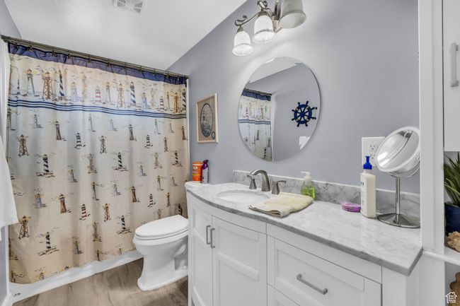 Full bathroom featuring visible vents, a shower with shower curtain, toilet, wood finished floors, and vanity | Image 11