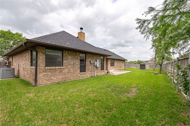 Back of house featuring a patio, a chimney, a storage shed, central AC, and a fenced backyard | Image 29