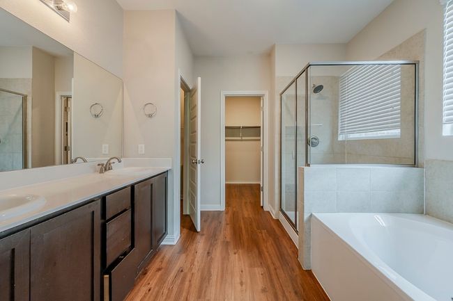 Bathroom featuring a sink, a garden tub, a stall shower, and wood finished floors | Image 15