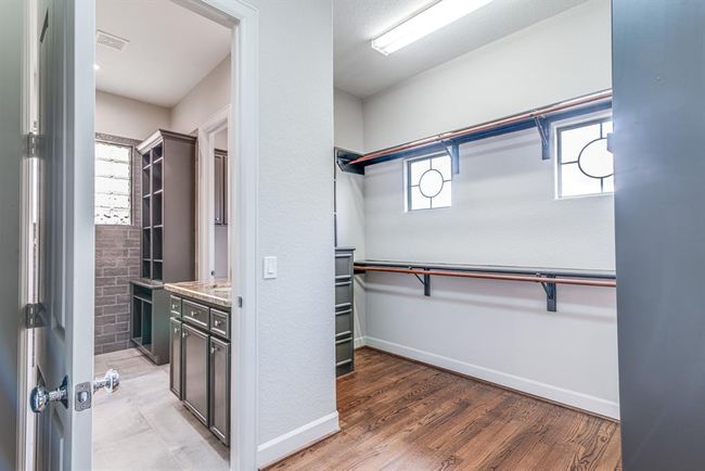 View from your dream walk in closet into the primary bathroom. Great storage and built in organization. Enjoy the added natural light. | Image 12